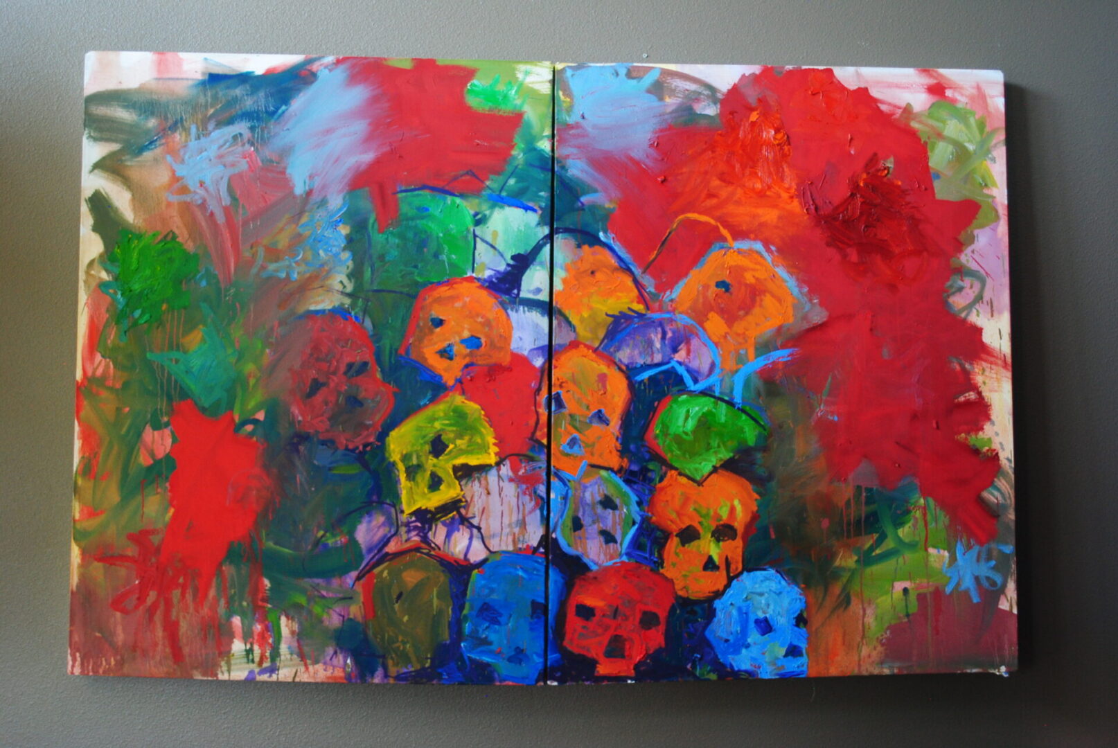 A painting of colorful skulls on two panels.